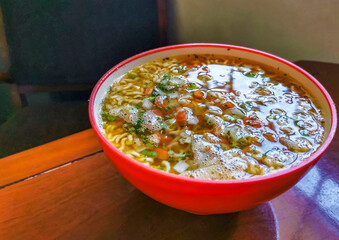 Noodle instant soup in pink bowl on brown wooden table.