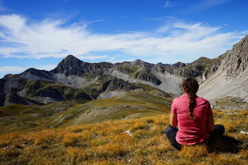 Hiker girl sitting on the top of Campo Imperatore mountains in an autumn day, Gran Sasso, Abruzzo, Italy