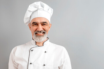 Chef-cooker in a chef's hat and jacket. Senior professional baker man wearing a chef's outfit. Character kitchener, pastry chef for advertising.