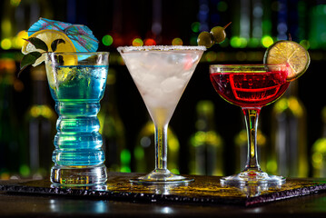 Set of coctails on bar counter in a restaurant, pub. Collection of fresh juice alcoholic drinks. Cooler beverage at nightclub on dark background