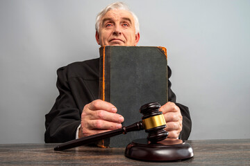 Judge holding a vintage law book, judge's gavel on the table. Law Lord wearing gown using a hammer for attention and verdict, justice judgment at courts of law