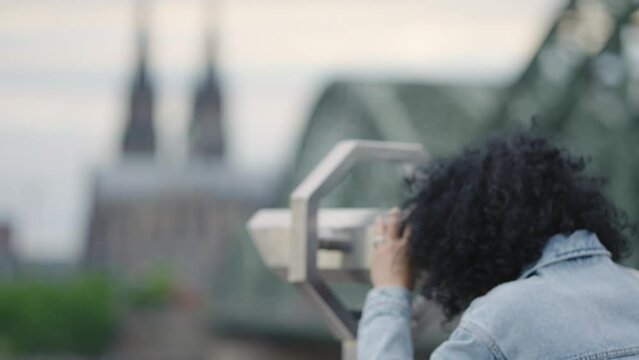 Tourist woman using coing binocular sightseeing a panoramic view of cityscape of Cologne with Hohenzollern bridge and Dom cathedral, Germany