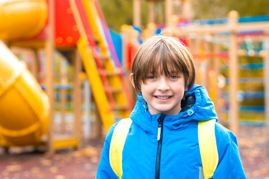 portrait of a smiling schoolboy in a jacket on the playground in autumn