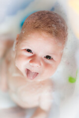 Baby bath time. Close-up detail view of mother bathing cute happy smiling baby in tub with water...