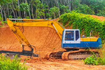 Big yellow excavator digs destroys forest jungle on Phuket Thailand.