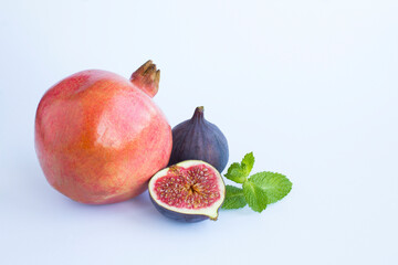 Close-up on pomegranate and  blue figs on the white background. Copy space.