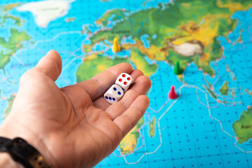 Hand rolls dice on colorful board games background, board game gaming moments