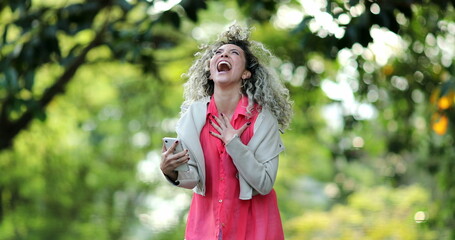 Hispanic woman jumping with joy celebrating success smartphone message