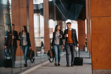 Business man and business woman talking and holding luggage traveling on a business trip, carrying fresh coffee in their hands.Business concept