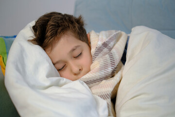 Sick ill little kid suffer from flu fever asleep in bed on lockdown quarantine. Unhealthy little boy child sleep in bed relax at home in bedroom.