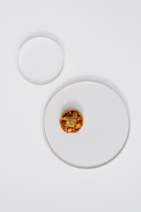 Photo of a delicious modern style handmade mini tart tartlet fulled with differ nuts like pistachio and hazelnut with salted caramel sause on a modern porcelain white flat plate on white background