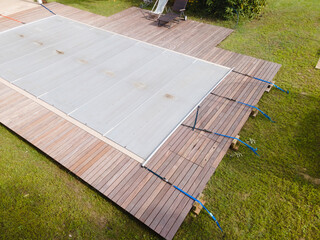 Drone photo of pool which is covered with grey pool tarpaulin, cover and prepared for winter and a...