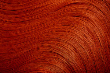 Red hair close-up as a background. Women's long orange hair. Beautifully styled wavy shiny curls. Hair coloring bright shades. Hairdressing procedures, extension.