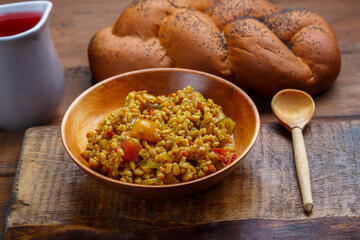Spelled with vegetables stewed in a wooden plate on a handmade wooden board.