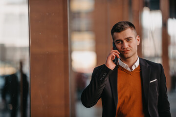 Going to airport terminal. Confident businessman traveler walking on city streets and pulling his suitcase drinking coffee and speaking on smartphone