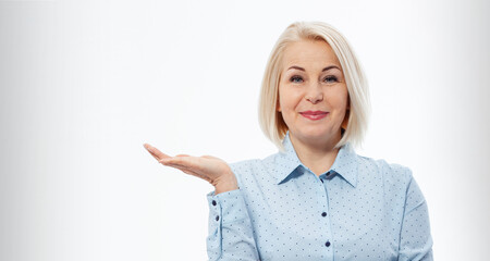 Photo of happy woman standing isolated over white wall background. Looking camera showing copyspace pointing.