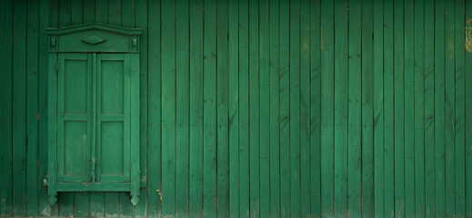 Horizontal banner with a wooden wall and a closed wooden window with shutters. Green wooden fence. Place for text. Old Russian village house in the Kazakh city of Pavlodar. Vintage. Copyspace
