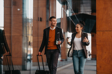 Business man and business woman talking and holding luggage traveling on a business trip, carrying...