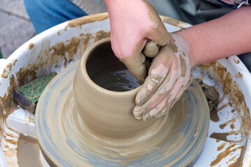 Close up hands working on pottery wheel and making a clay pot, selective focus