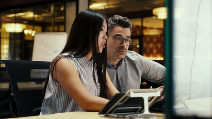 Multi-ethnic creative coworkers working on business project in modern office using laptop and digital tablet computer. Businesspeople discussing startup in e-commerce company.