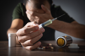 Drug addict man with a syringe and drugs. Addiction