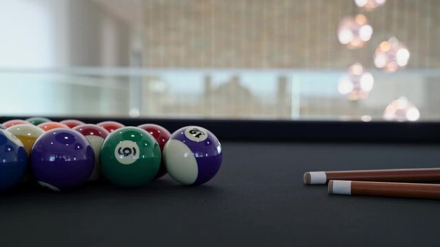 Multicolored billiard balls snooker with cues on the table with blurred background on the game room