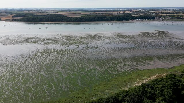 Aerial shot of a frozen seashore with a forest and boats in the distance