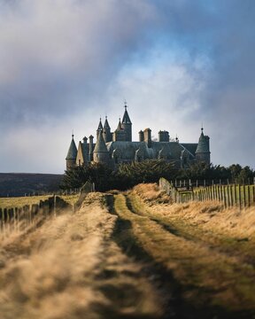 Vertical closeup of Veves Castle with yellow grass around and cloudy sky background