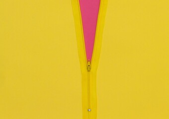 Yellow zipper unzipped half way showing pink color under a yellow background © Ivan Radić/Wirestock Creators