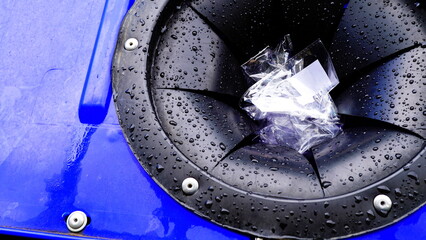 Detail of the rubber slot of a recycling bin covered in raindrops with jammed plastic. conceptual...
