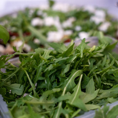 
Gray plate with salad of arugula, beets, Greek cheese on a white kitchen table. Healthy vegetarian food.