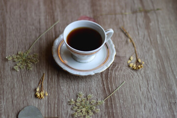 Cup of tea and pressed flowers on wooden table. Selective focus.