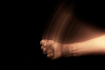 fist hitting the table. hand and forearm with motion trail on black background.