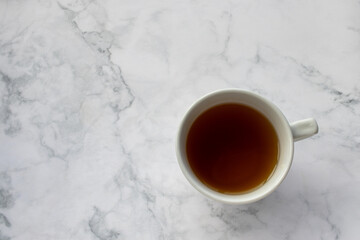 Cup of tea on table. Green herbal tea in mug on white marble background. Top view, copy space. Traditional teatime 