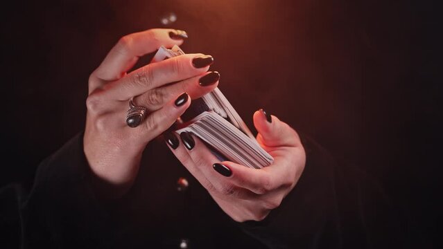 Woman witch shuffles tarot deck, preparation for consultation on predicting future destiny. Fortune teller, medium, divination cards. 