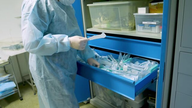 The hands of a doctor in gloves lay out sterile surgical instruments packed in vacuum bags. Hands clean the disinfected tool in the box. The concept of sterilization of a surgical instrument.