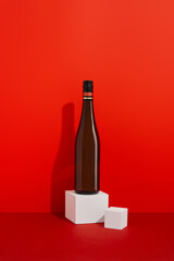 Bottle of wine on red background with deep shadows. Mock up drink with place for you lable and text