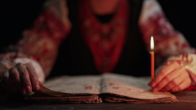 Ukrainian woman reading ancient book - Bible. Concentrated attentively follows finger on paper page under candle light. History of Kyiv Rus. Psalter, 19th century, prayers and psalms
