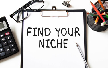 FIND YOUR NICHE. text on white paper on a gray background near glasses, pens, calulator