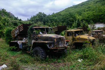 Fototapeta premium Old abandoned rusty military trucks overgrown by plants