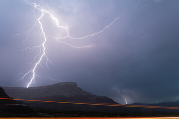 A bolt of lightning splits in the sky. Part of it comes down to the top of Smith's mesa in Southern...