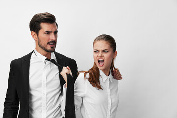 Man and woman pulling on tie anger business looking at each other screaming with hands up in white isolated background. The concept of business in a couple harassment startup copy space