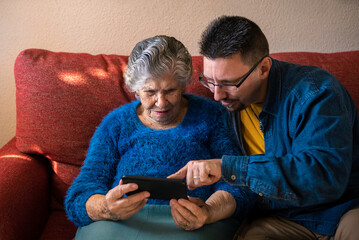 Grandma holding smartphone to call with her grandson sitting on living room.