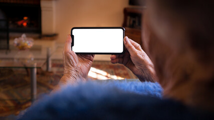 Old woman hands holds a smartphone with white empty screen for your mockup