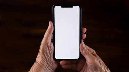 Old woman at home using a mobile phone with white screen. Mockup device