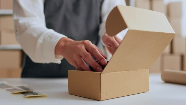 Packing goods for shipment by country, Post office employee of the company packs the goods for shipment, e-commerce sending goods to customers, Close-up hand closes the box

