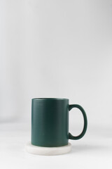 Green ceramic cup on a white marble saucer, Green mug