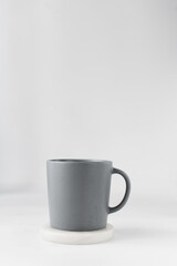 Grey ceramic cup on a white marble saucer, Grey mug