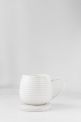 Obraz na płótnie Canvas white ceramic cup on a white marble saucer, white teacup