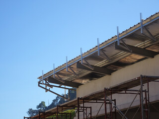 Naklejka premium MELAKA, MALAYSIA - SEPTEMBER 16, 2022: Installation of the aluminum cladding frame at the end of the roof is underway. The metal decking roof system is equipped with a heat-resistant silsalation layer